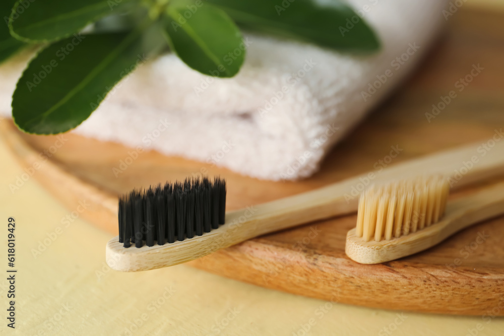 Bamboo tooth brushes and towel on beige background, closeup