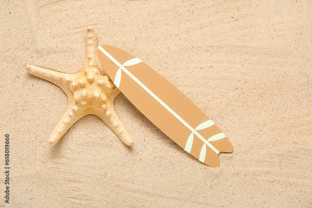 Mini surfboard with starfish on sand