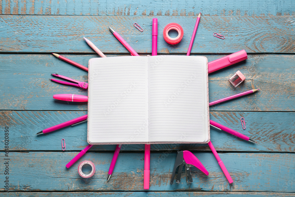 Notebook with frame made of different stationery on blue wooden background