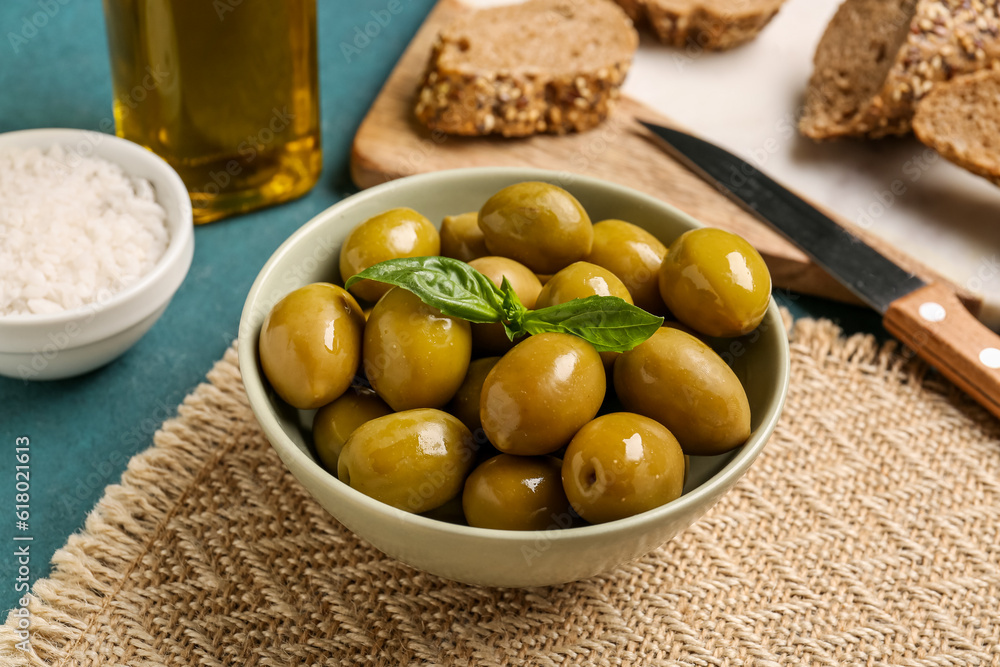 Bowl with ripe olives on green background