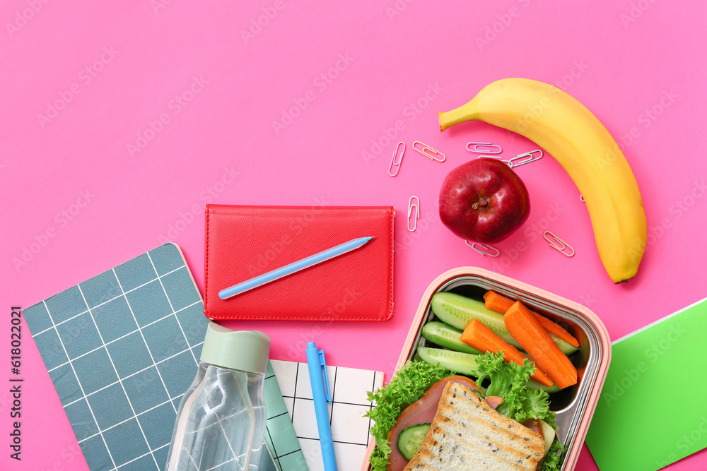 Different stationery, drink and lunch box with tasty food on pink background