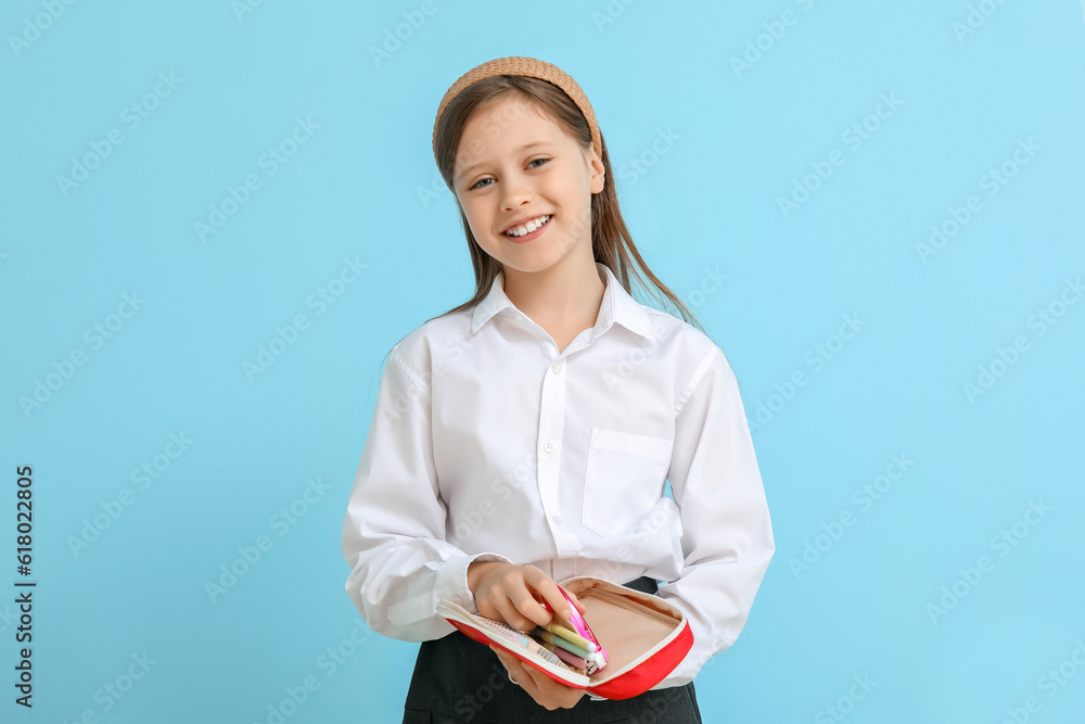 Little schoolgirl with pencil case on blue background