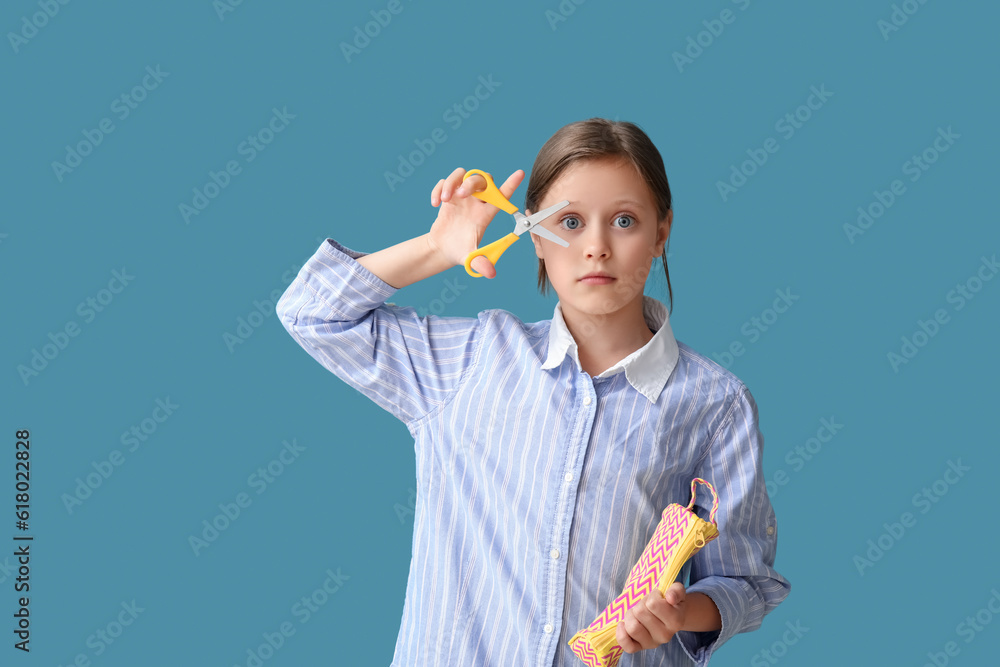 Little schoolgirl with scissors and pencil case on blue background