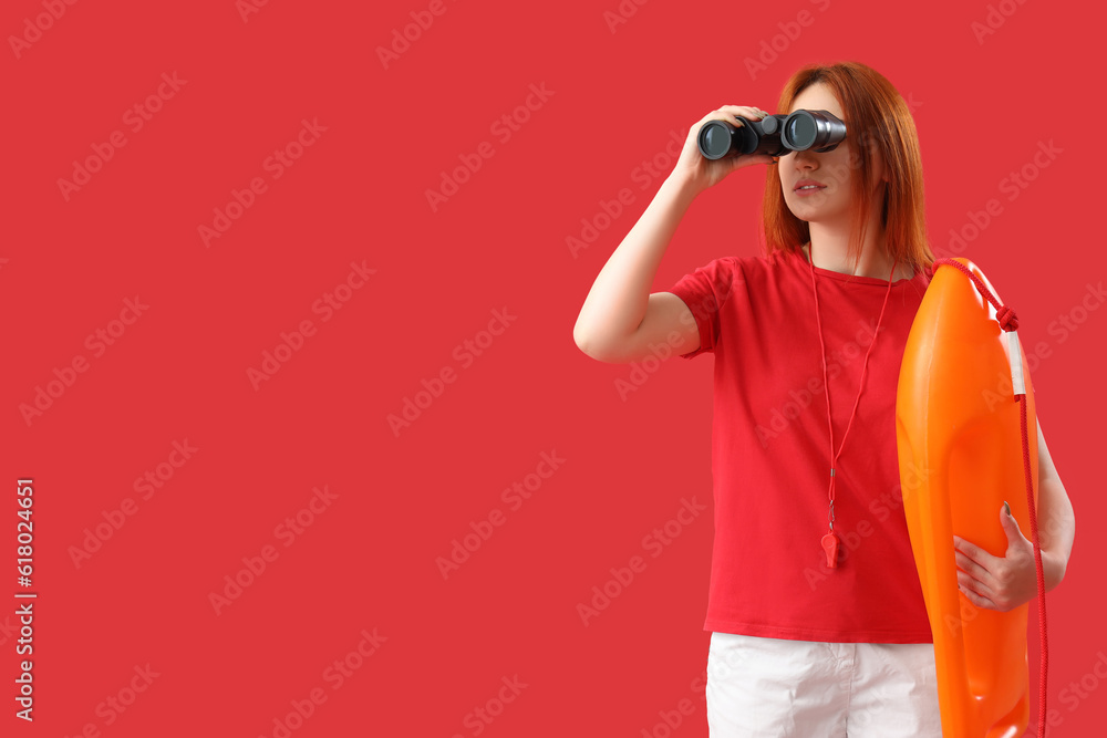 Female lifeguard with binoculars and rescue buoy on red background