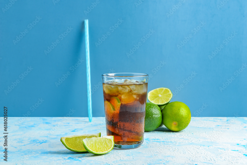 Glass of cold Cuba Libre cocktail on blue background