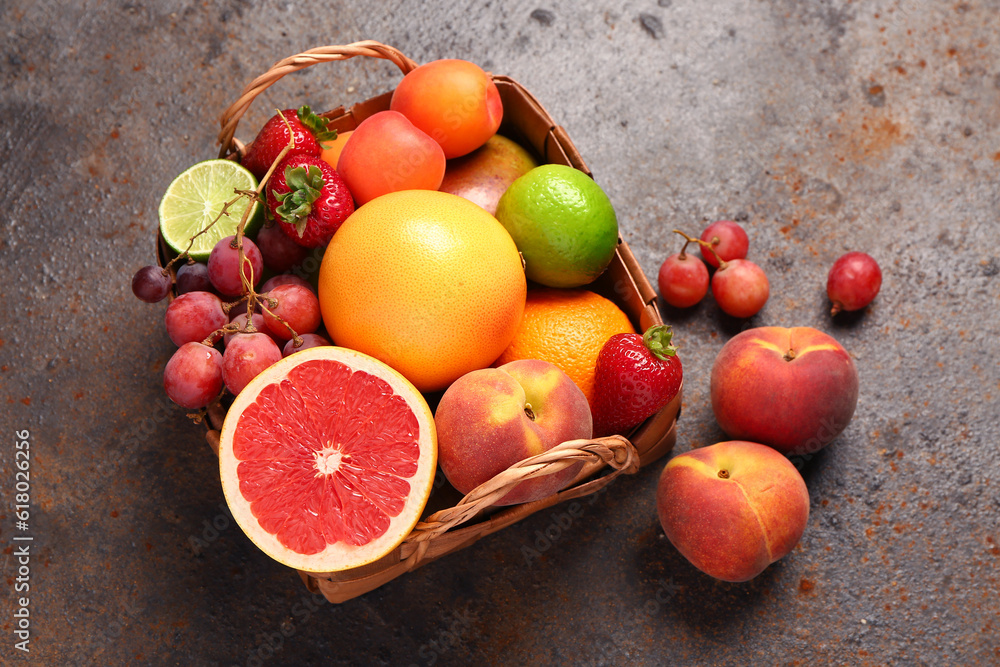 Wicker basket with different fresh fruits on dark table