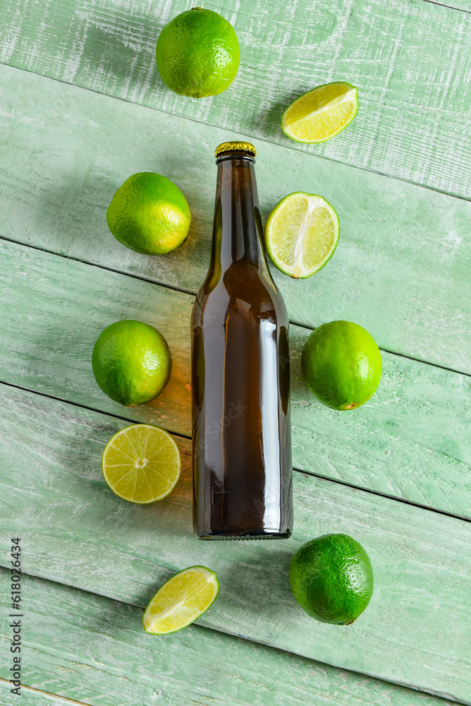 Bottle of cold beer with lime on green wooden background