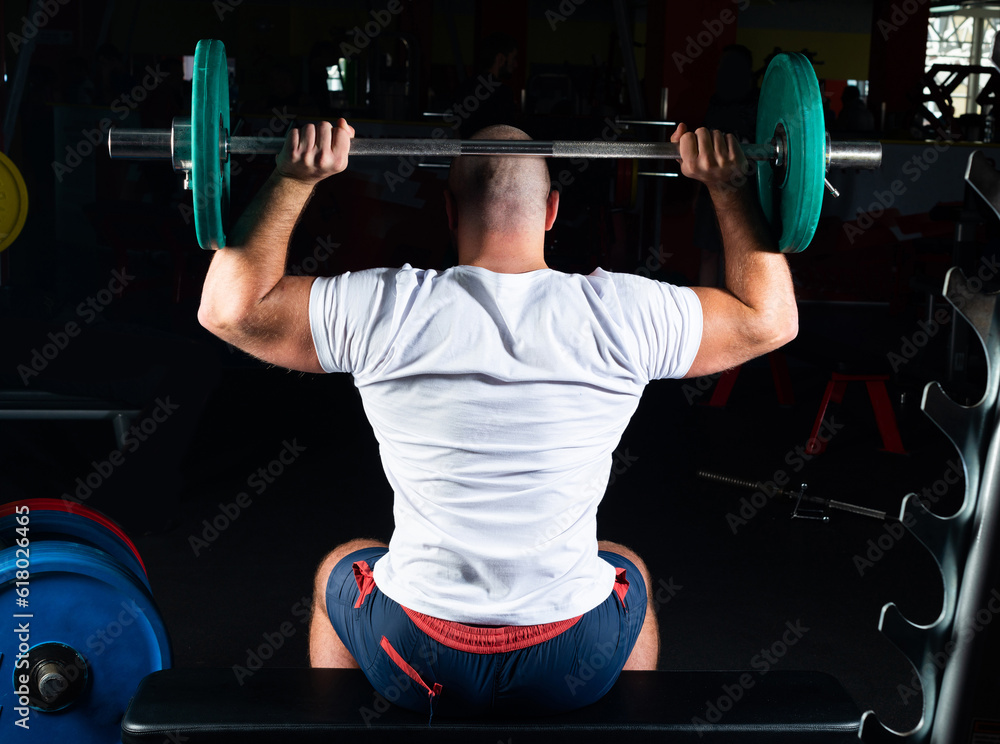 Male athlete lifts the barbell