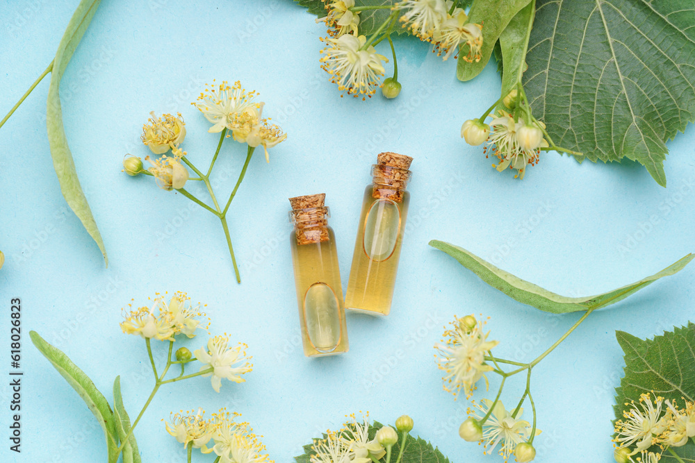 Composition with bottles of essential oil and aromatic linden flowers on color background