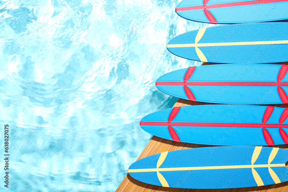 Composition with mini surfboards on edge of swimming pool