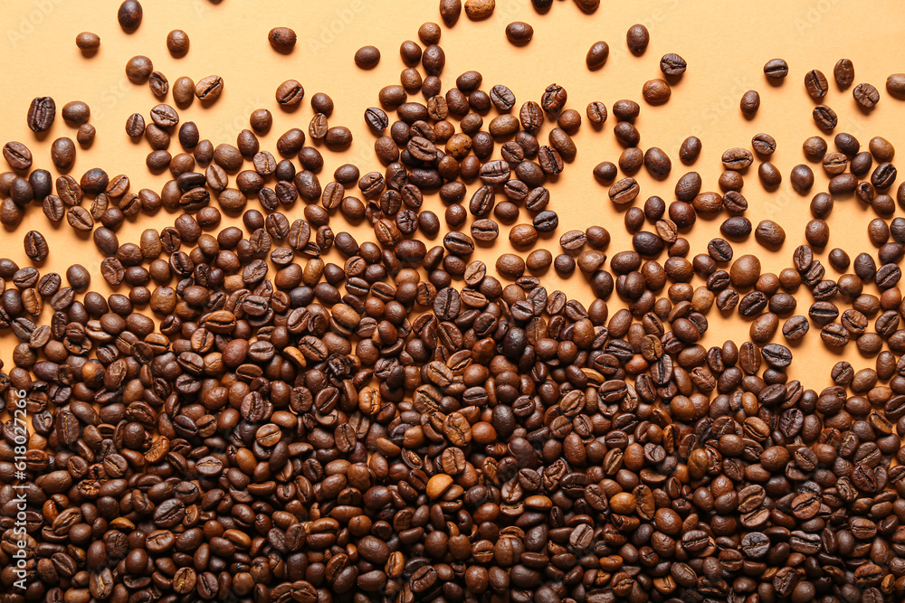 Scattered coffee beans on orange background