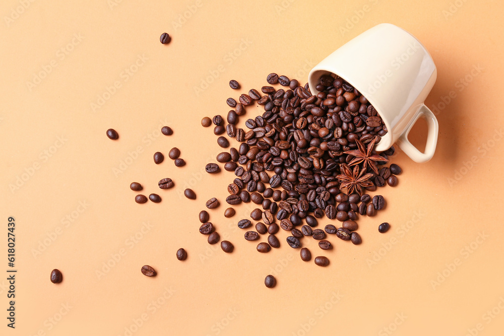 Cup with scattered coffee beans and star anise on orange background