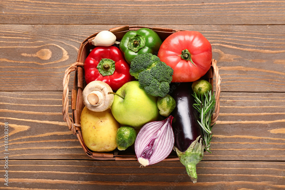 Wicker basket with fresh ripe vegetables on wooden background