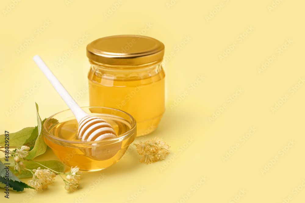 Jar and glass bowl with linden honey on yellow background