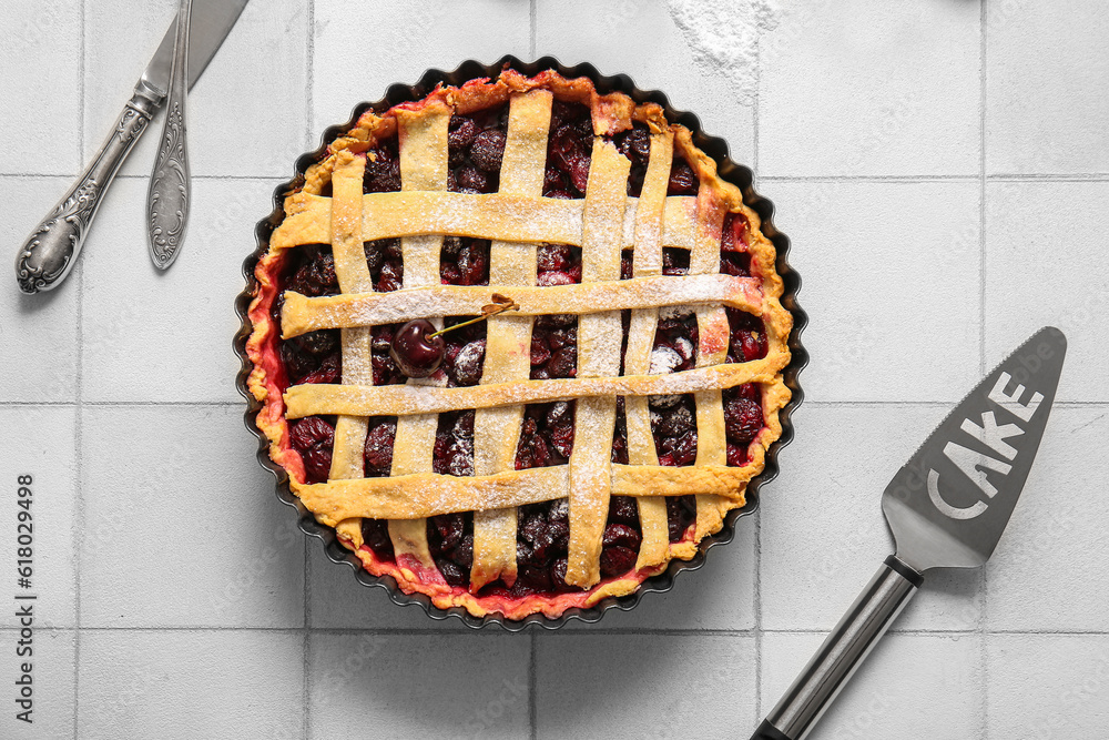 Baking dish with tasty cherry pie on white tile background