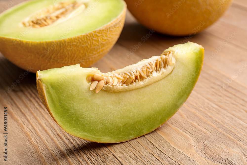 Half of sweet melon with piece on wooden background