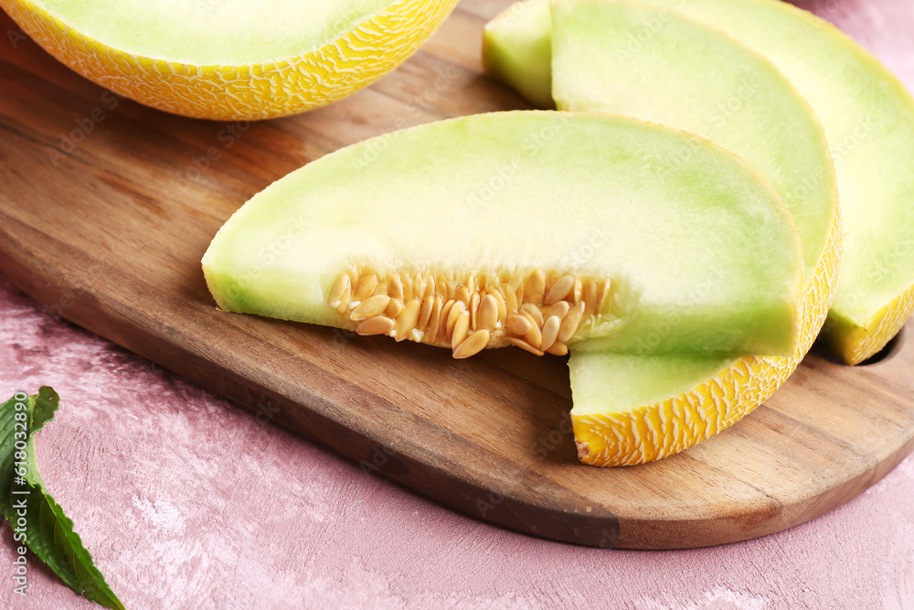 Wooden board with pieces of sweet melon on purple background, closeup