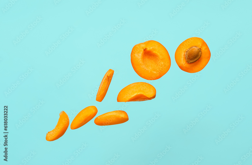 Flying halves of fresh apricot with pieces on blue background