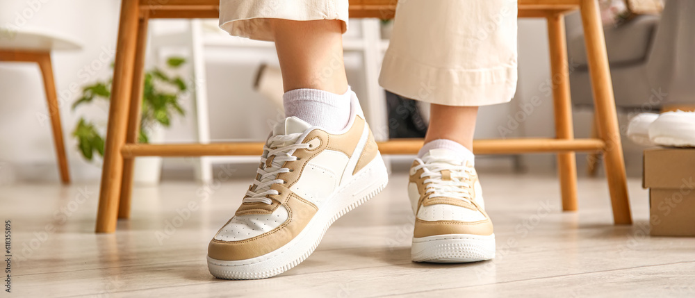 Woman trying on stylish sneakers in boutique