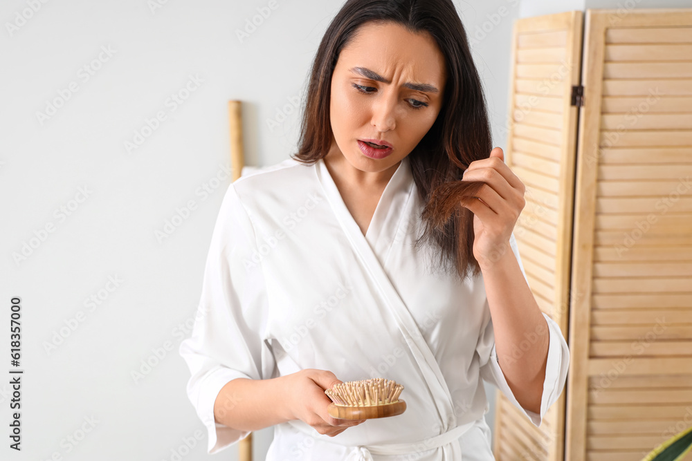 Worried young woman with hair loss problem in bathroom