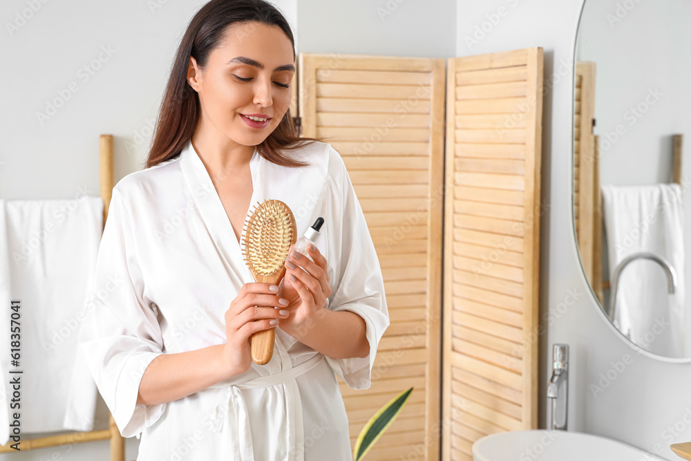 Woman with serum for hair loss treatment and brush at home