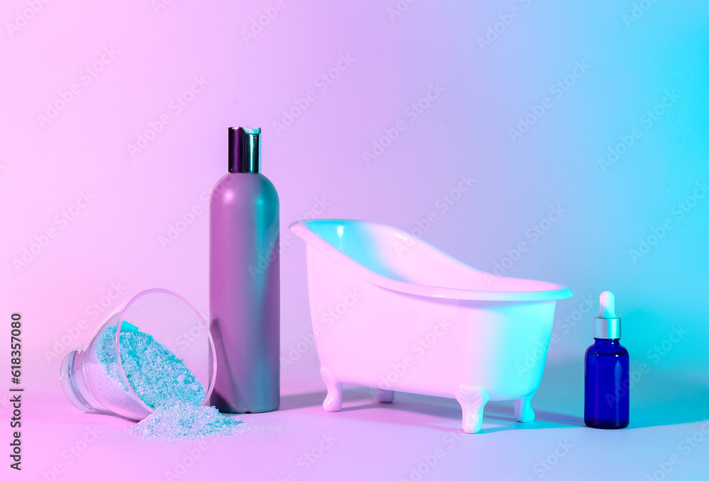 Small bathtub and cosmetic products on color background