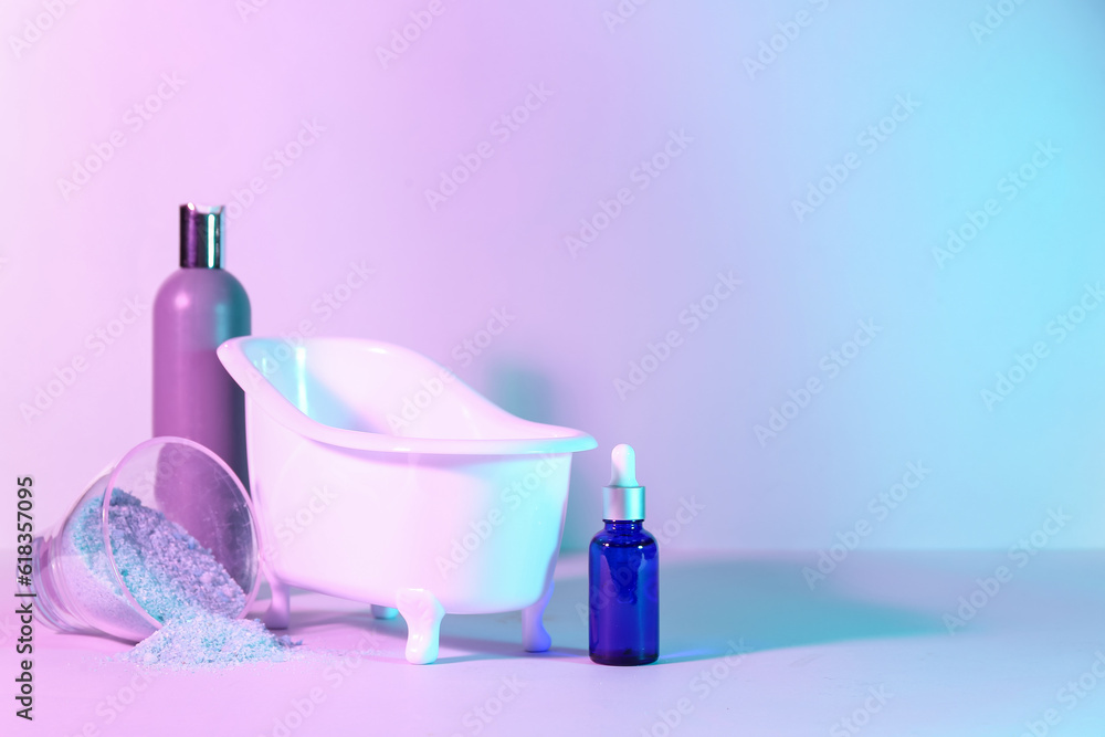 Small bathtub and cosmetic products on color background