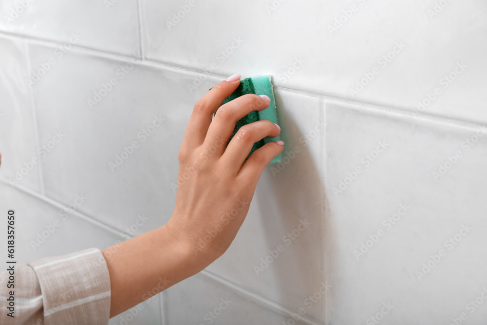 Woman cleaning light tile with sponge and baking soda, closeup