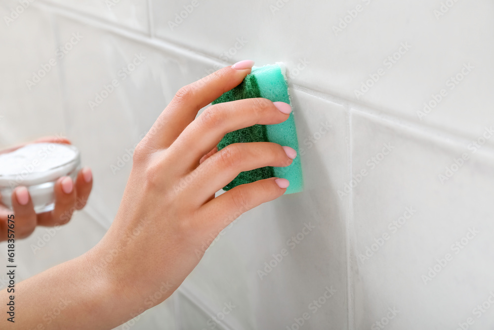 Woman cleaning light tile with sponge and baking soda, closeup