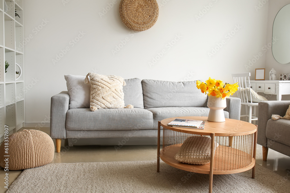 Interior of modern living room with cozy sofa and flower vase on coffee table