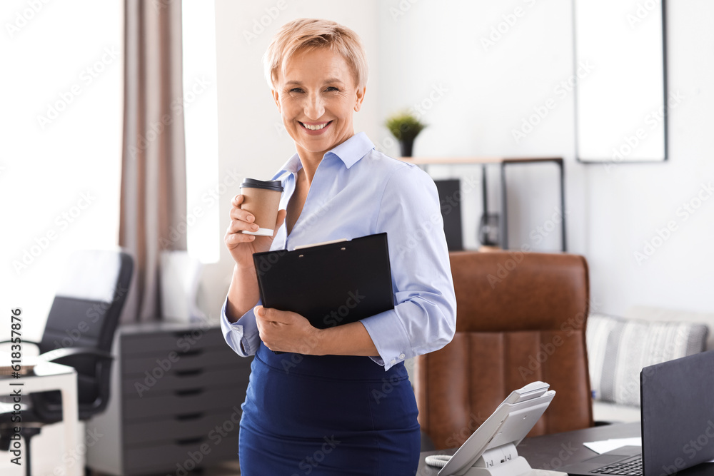 Mature businesswoman with documents and coffee in office