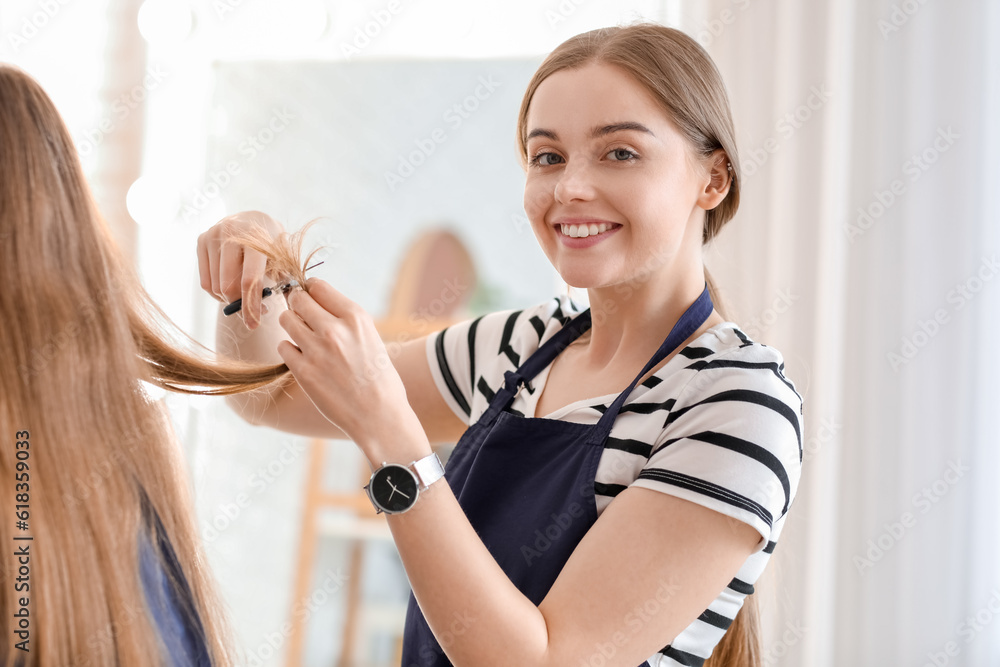 Female hairdresser cutting young womans hair in beauty salon