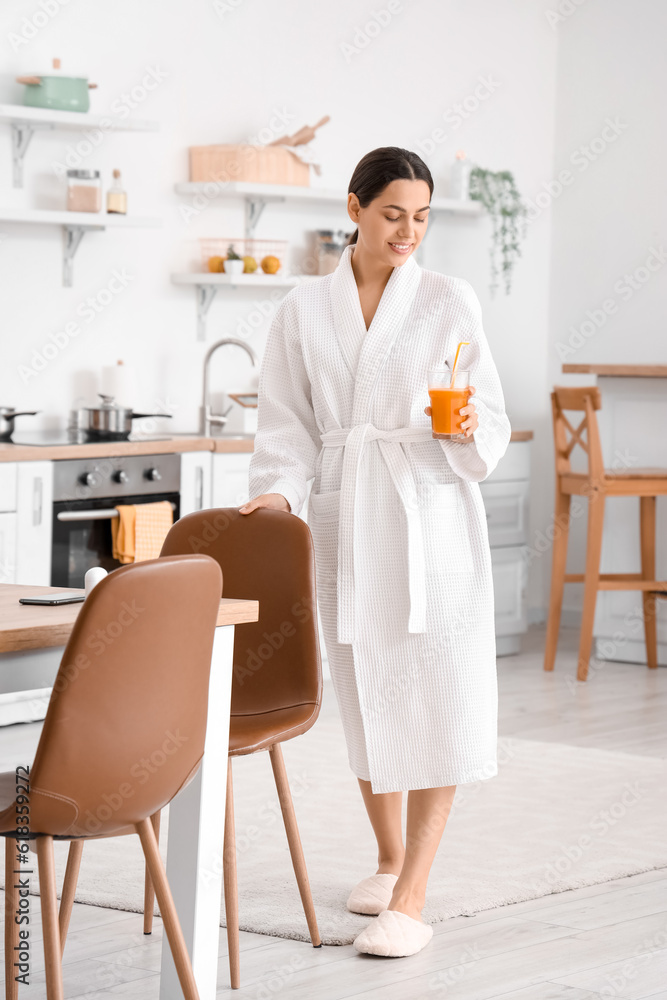 Young woman with glass of vegetable juice in kitchen