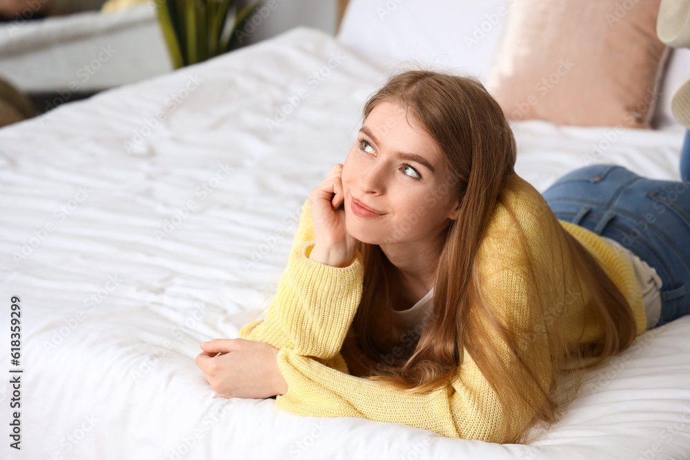 Dreaming young woman lying on bed at home