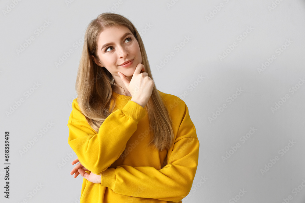 Dreaming young woman on light background