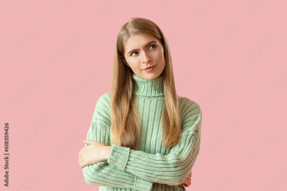 Thoughtful young woman on pink background