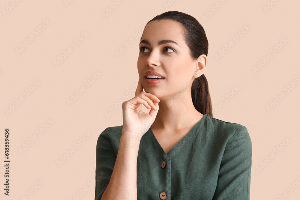 Thoughtful young woman on beige background, closeup