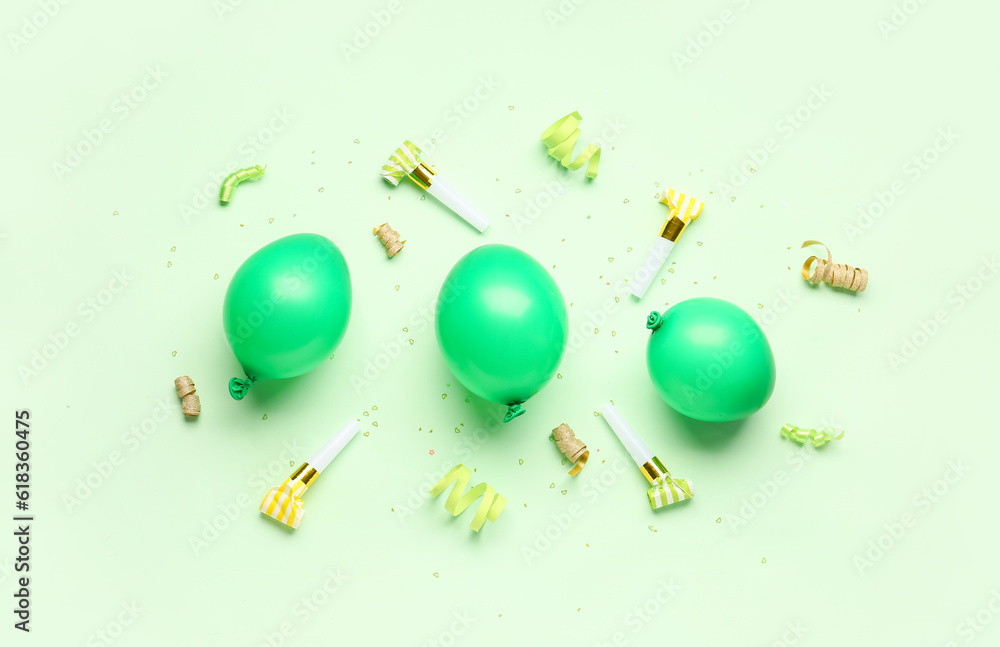 Balloons and whistles for birthday party on pale green background