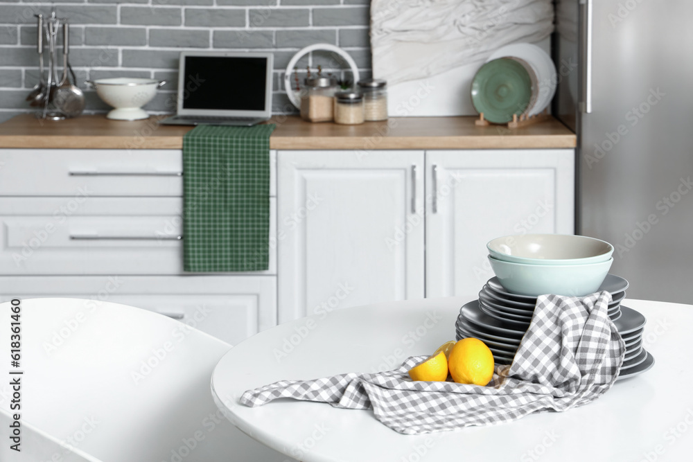 Table with lemons and plates in light kitchen, closeup