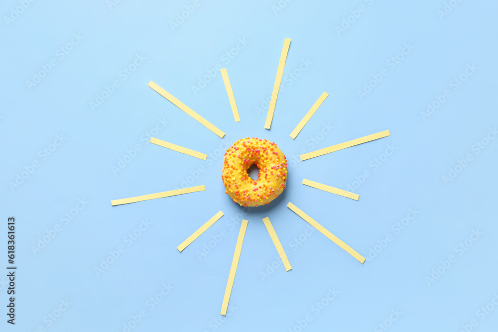 Creative composition with sun made of sweet donut on blue background