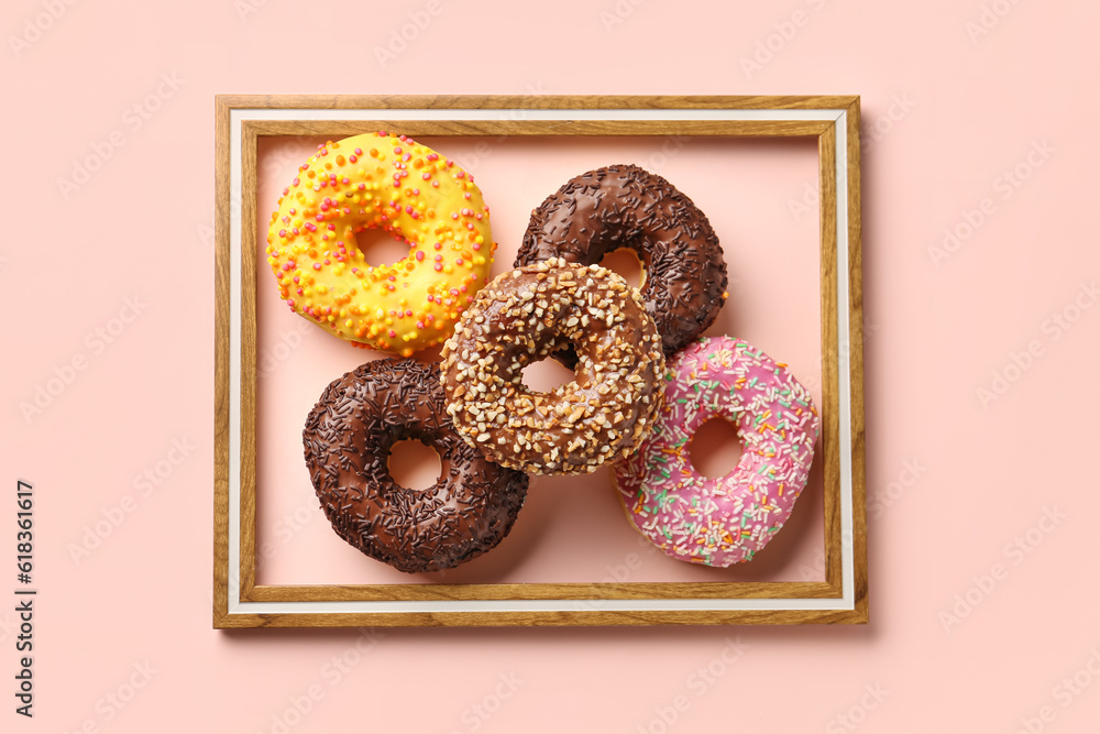 Photo frame and sweet donuts on pink background