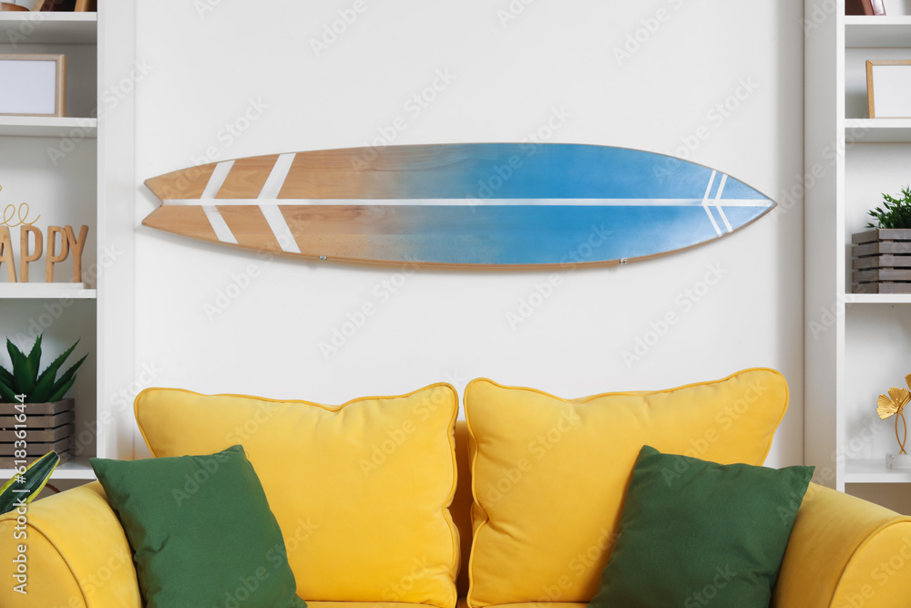 Interior of light living room with surfboard and yellow sofa