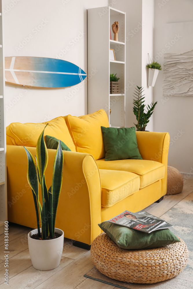 Interior of light living room with surfboard and yellow sofa