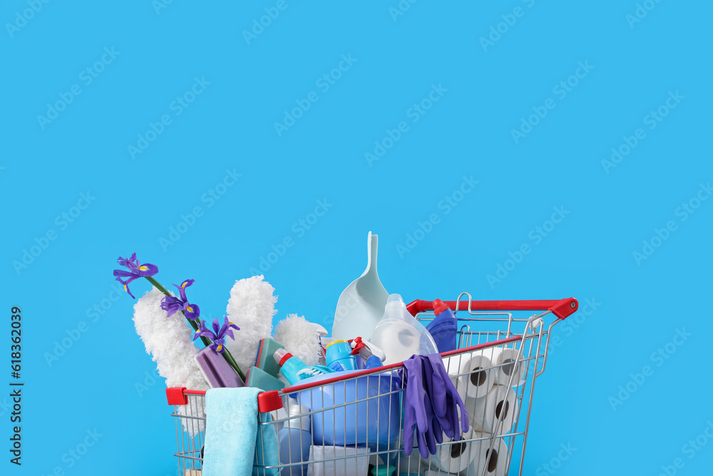 Shopping cart full of cleaning supplies and purple flowers on blue background