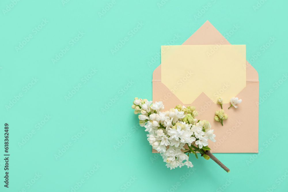 Envelope with blank card and lilac flowers on turquoise background