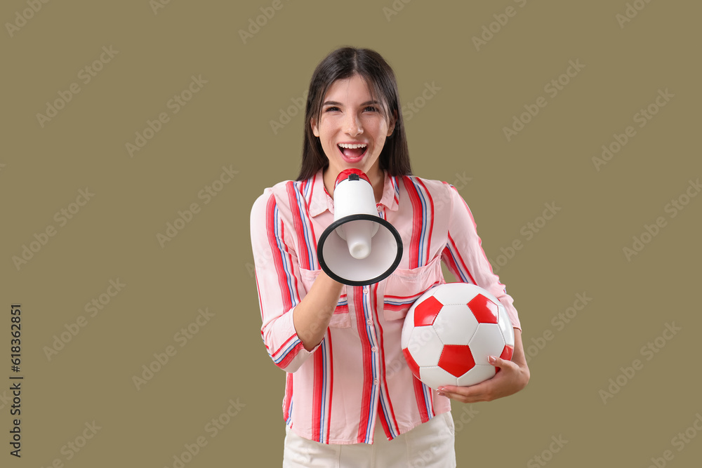 Young woman with soccer ball and megaphone on color background