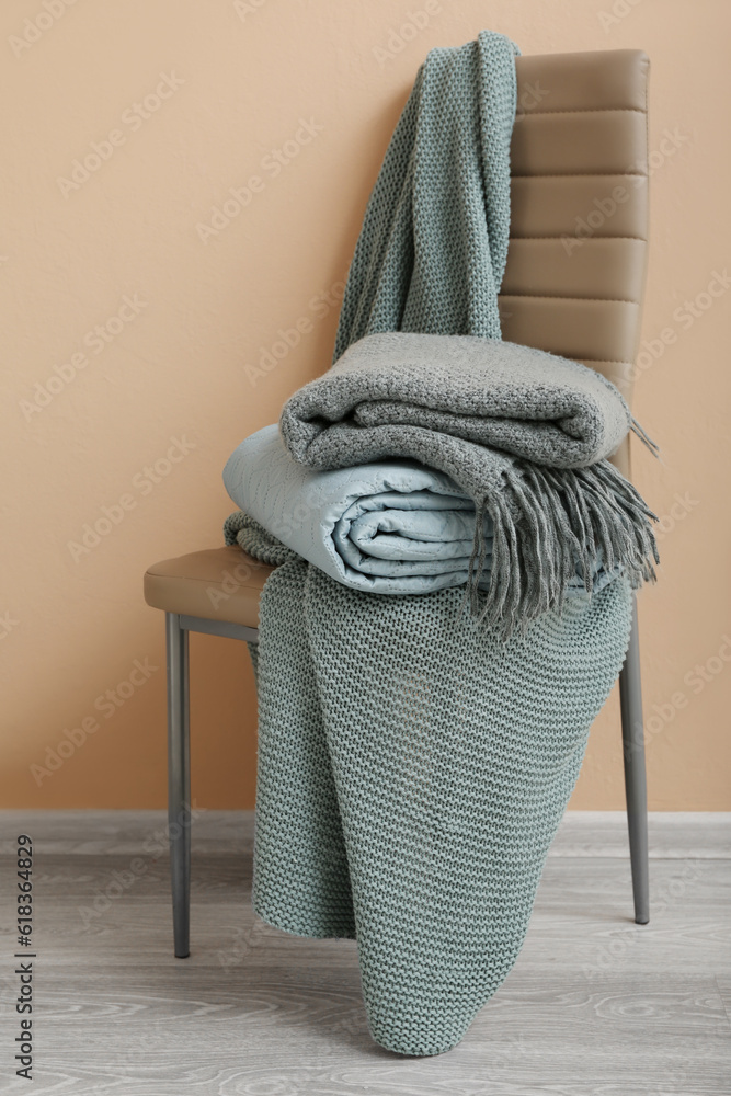 New soft folded blankets on chair near beige wall in room