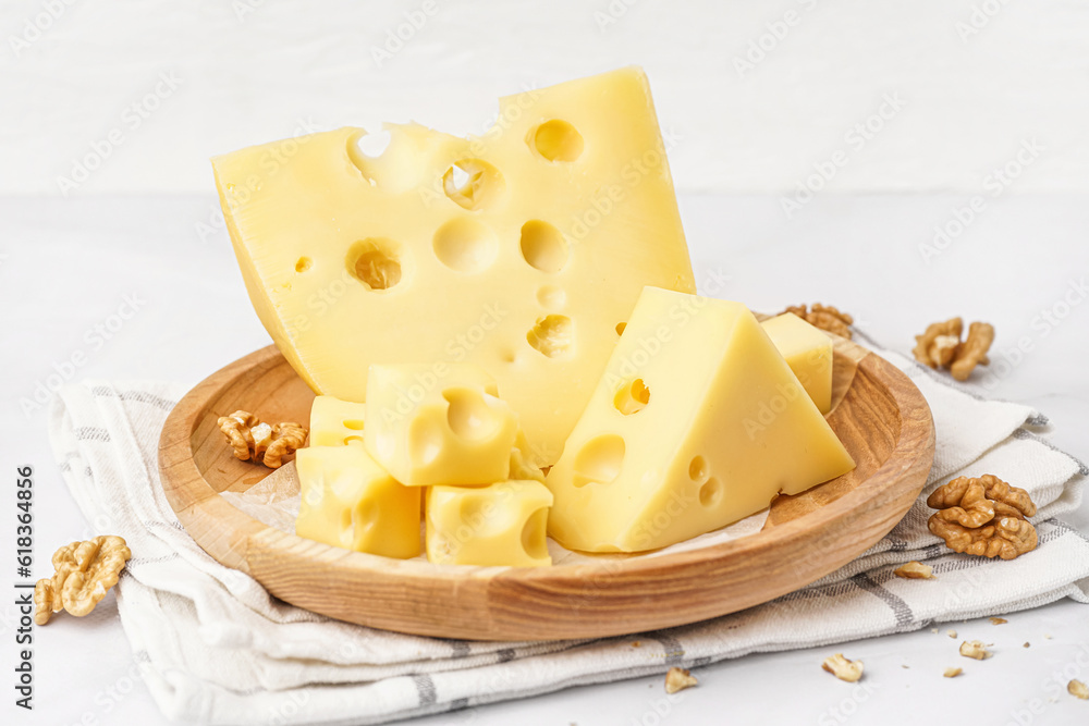 Plate with pieces of Swiss cheese and walnut on white background