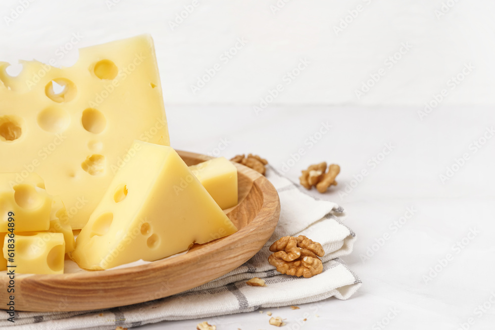 Plate with pieces of Swiss cheese and walnut on white background