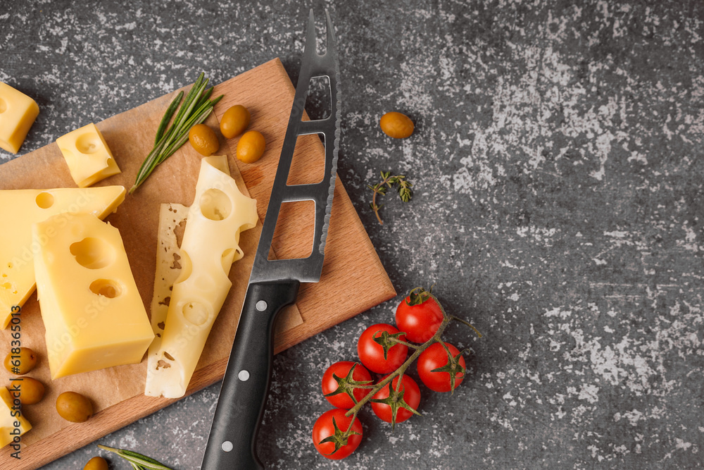 Board with pieces of Swiss cheese and olives on grey background